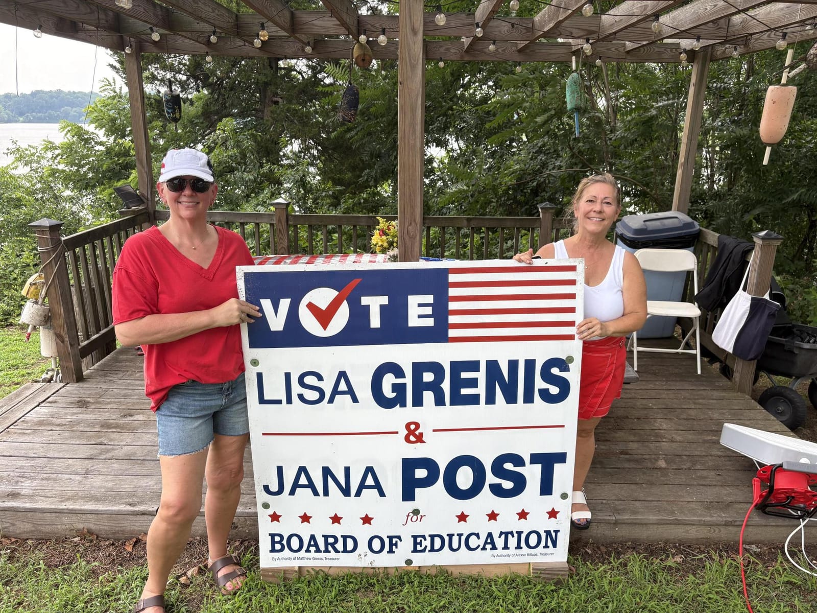 Lisa Grenis and Jana Post with their campaign sign at a waterfront pavilion